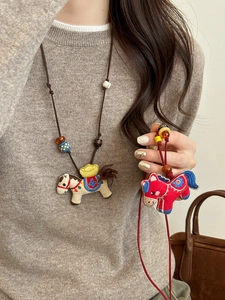 Detailed view of handmade embroidered horse pendant with decorative ceramic and wooden beads
