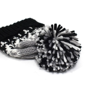 Detail eines flauschigen dreifarbigen Pompons auf einer Strickmütze in Schwarz, Grau und Weiß
