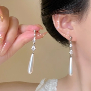 Detail shot of elegant long drop earrings with crystals and white teardrop pearls