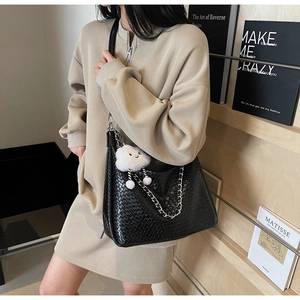 Detail of black woven shoulder bag with gold chain and white plush cloud charm