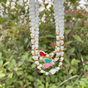 Detailed shot of multi-layer beaded necklace with colorful fish charms and white pearls