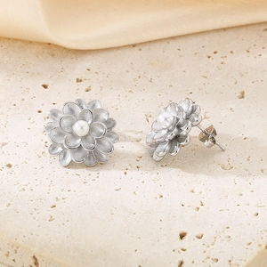 Detail of matte silver flower earrings with multi-layer petals and a centered pearl