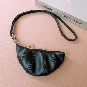Macro shot of black PU leather croissant pendant with soft pleated texture and silver zipper