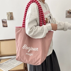 Detailed view of pink canvas tote bag featuring striped plush handles and Bonjour Magic print