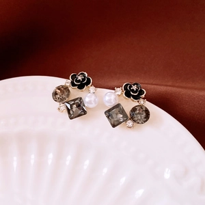 Detail of French vintage earrings with black flowers, pearls, and crystals on a white plate