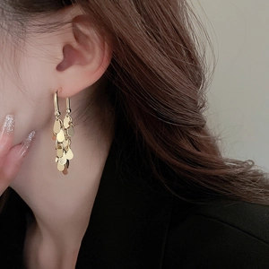 Close-up of gold-plated sequin fringe earrings showing shimmering metal layers and movement