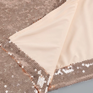 Detailed close-up of rose gold sequins with stitching on beige woven lining fabric