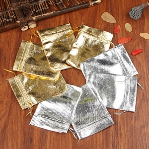 Detailed view of gold and silver drawstring jewelry gift pouches on a wooden background