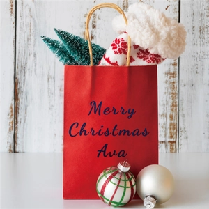 Detail of red Christmas gift bag with gold glitter letters and festive ornaments