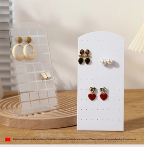 Detailed macro view of white and clear acrylic earring organizer stands on a wooden desk