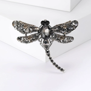Detailed studio shot of a dragonfly brooch featuring black and grey crystal accents