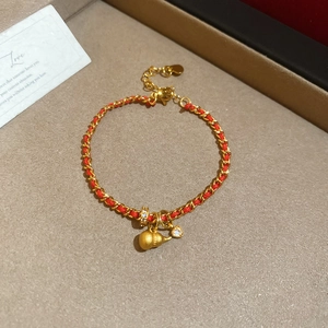 Dettaglio del bracciale a catena d'oro intrecciata rossa con ciondolo a zucca e cuore