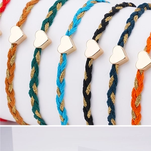Detail of colorful hand-woven friendship bracelets with golden heart charms on a white stand
