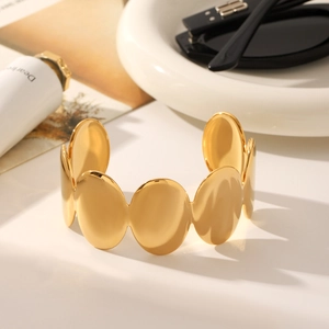 Detail of 18K gold-plated oval linked bangle with polished metallic finish