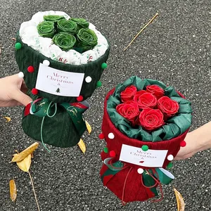 Christmas bouquet with red and green roses wrapped in festive knit fabric with pom-poms