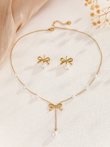 Close-up of elegant gold bow pendant and pearl necklace set on champagne velvet