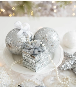 Close-up of sparkling silver foam Christmas ornaments and mosaic gifts on a ceramic tray