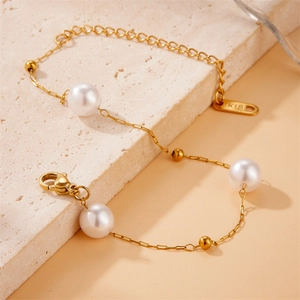 Detailed macro view of an 18K gold-plated chain bracelet with white pearls and K18 tag