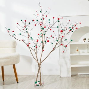 Christmas dry branch decor with red, green and white pom poms in glass vase
