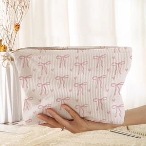 Detail showing soft corduroy texture and pink bow patterns on the compact makeup bag
