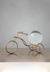 Detailed view of a golden metal tricycle ornament holding a clear crystal sphere