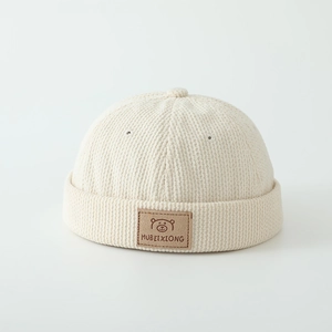 Detailed view of cream corduroy docker hat with bear patch and ribbed texture