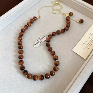 Detail of adjustable gold chain and tiger eye beads with shimmering chatoyancy effect