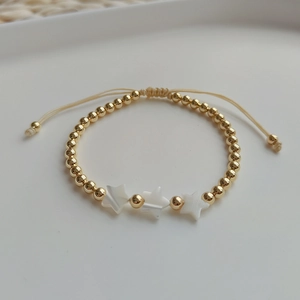 Adjustable gold bead bracelet featuring white shell star charms on a woven cord band