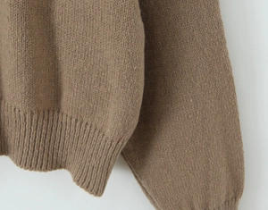 Close-up of brown knit cardigan featuring detailed ribbed cuffs and hem texture