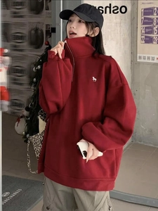 Λεπτομέρεια από μπορντό oversized φούτερ με μισό φερμουάρ και κέντημα μονόκερου
