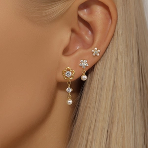 Detail of S925 silver gold floral earrings with pearls and zircons on a model
