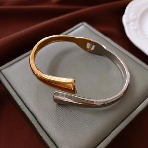 Detail shot of two-tone gold and silver drop bangle with spring hinge on jewelry box