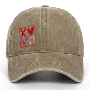 Dettaglio del ricamo XOXO e del motivo a cuore su un cappellino in cotone lavato