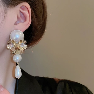 Detail view of retro pearl drop earrings with golden hollow flower and zircon stones