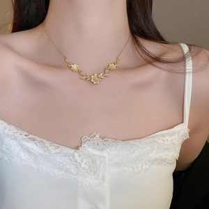 Close-up of gold hollow flower pendant necklace with diamonds on a model neck