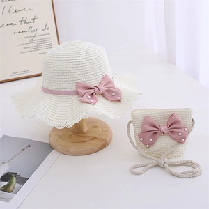 Close-up of girls straw hat and bag set with pink bows and pearls on lace trim