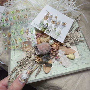 Detail of embossed green butterfly nail stickers with vintage floral and pearl accents