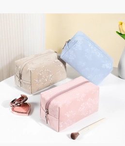 Detailed view of floral embossed PU leather cosmetic bags in pink, blue, and cream colors