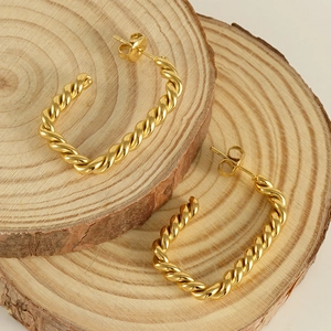 Détails de boucles d'oreilles créoles torsadées plaquées or 18 carats sur bois rustique