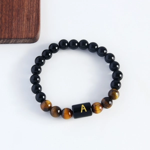 Tiger eye and black obsidian beaded bracelet featuring a gold letter A charm on white back