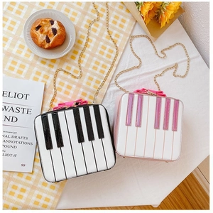 Detail view of piano keyboard shoulder bags with bow decoration and gold chain strap