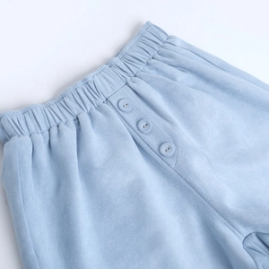 Detail of light blue elastic waist with three decorative buttons on soft suede fabric