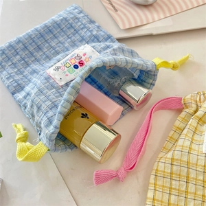 Detailed close-up of a blue checkered drawstring storage bag with cute SOKA label design