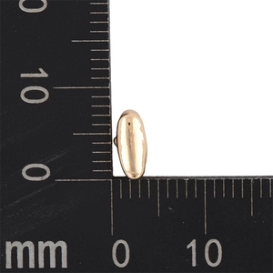 Macro shot of gold KC bubble alphabet pendant measuring 8mm x 4mm on a scale ruler