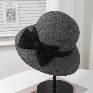 Close-up of grey straw sun hat featuring a large black satin bow on metal stand