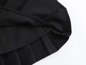 Detailed close-up of neat pleated texture and stitching on black faux leather skirt