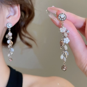 Orecchini pendenti con fiori bianchi e perline trasparenti indossati per mostrare lo stile