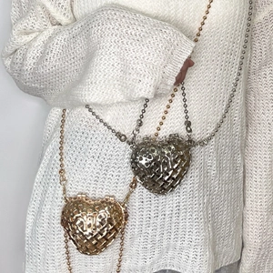 Detailed view of hollow heart metal clutch bags in gold and silver with ball chains