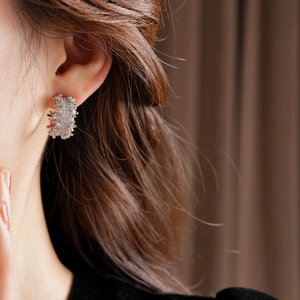 Detailed close-up of C-shaped silver earrings with micro-inlaid cubic zirconia
