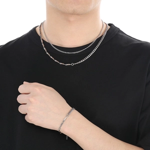 Detail of silver stainless steel Cuban link and geometric bar necklace set on model